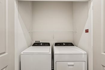 Two white front loading washing machines in a small laundry room